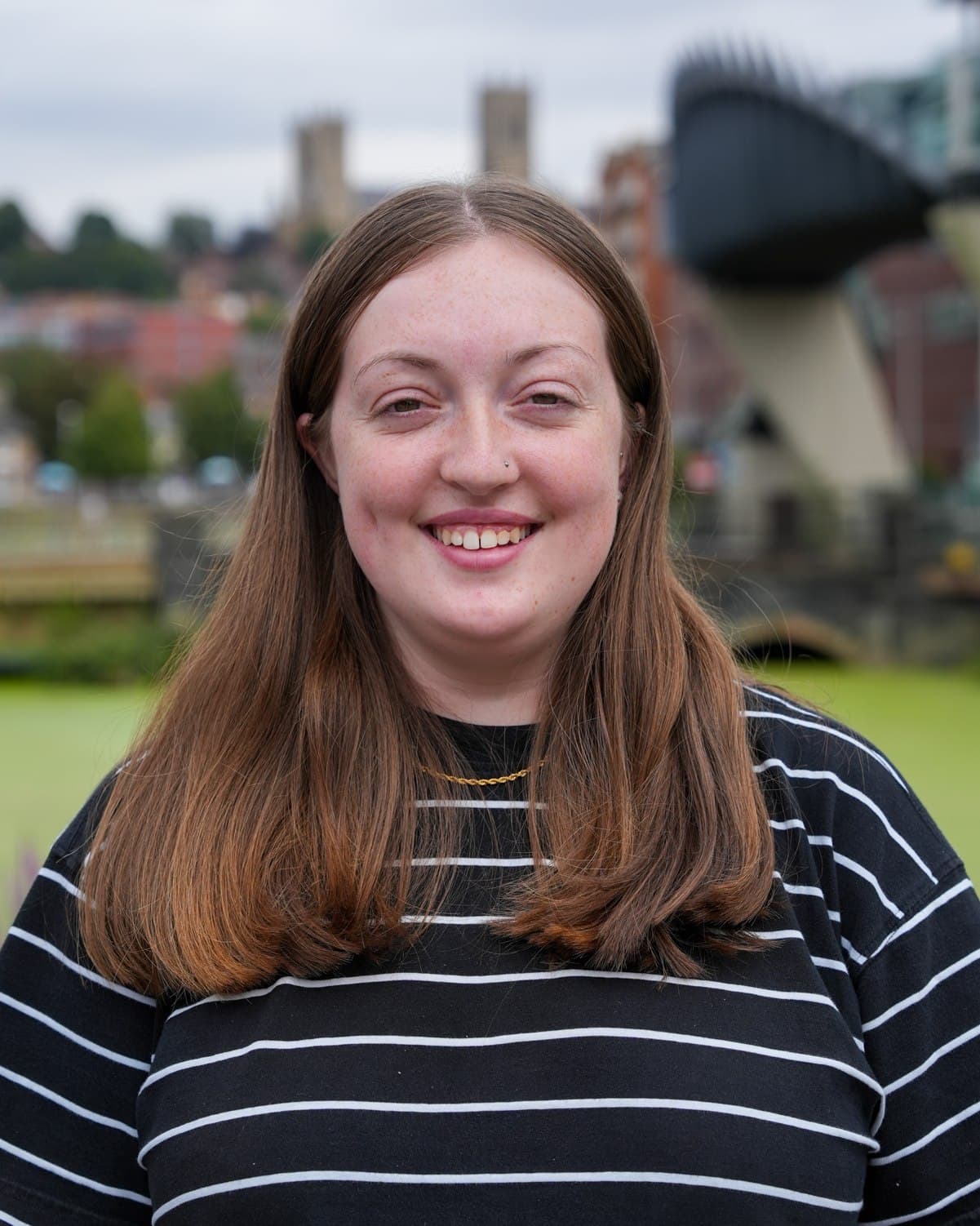 A smiling member of the Identity Agency team, photographed by the waterfront with Lincoln Cathedral behind.
