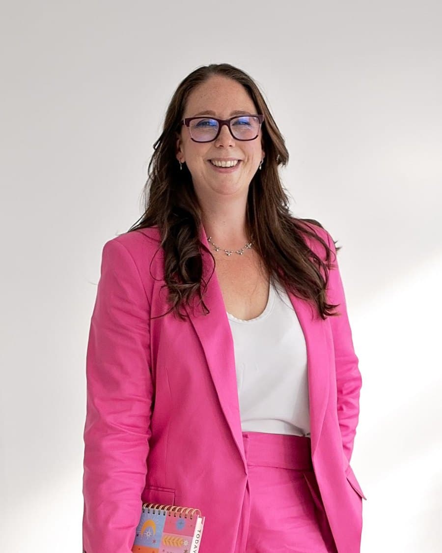 Claire Lockey, host of The Business of You, smiling in a pink suit.